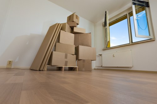Mover carrying boxed belongings through a narrow staircase in Frognal