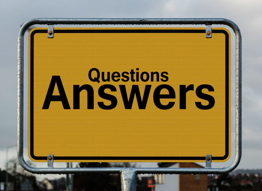 A large rectangular yellow road sign with a metal frame, displaying the words 'Questions Answers' in bold black text. The sign is positioned outdoors against a cloudy sky, mounted on a pole. In the background, faint outlines of buildings and trees are visible, indicating an urban or semi-urban environment. The sign's purpose is to direct viewers toward informational content, which may relate to items such as house removals, relocation services, or moving guidelines, supporting the context of home and furniture transport. This image is associated with [DOMAIN], referencing the page titled 'Do I Need a Skip or Permit in Frognal? Local Rules Answered,' and is relevant to logistical considerations involved in local house removals performed by companies like [COMPANY_NAME].